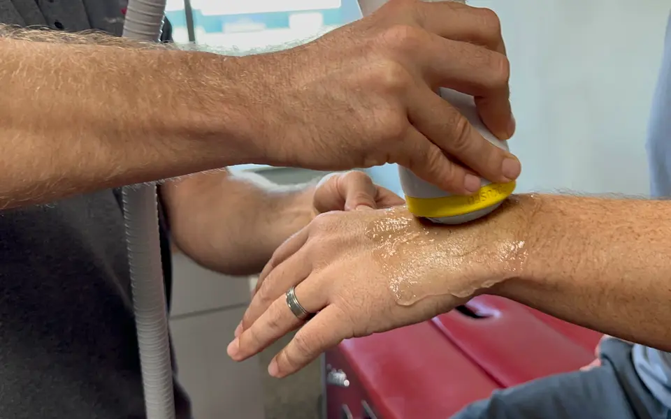 SoftWave applicator treating the back of a patient’s wrist and hand